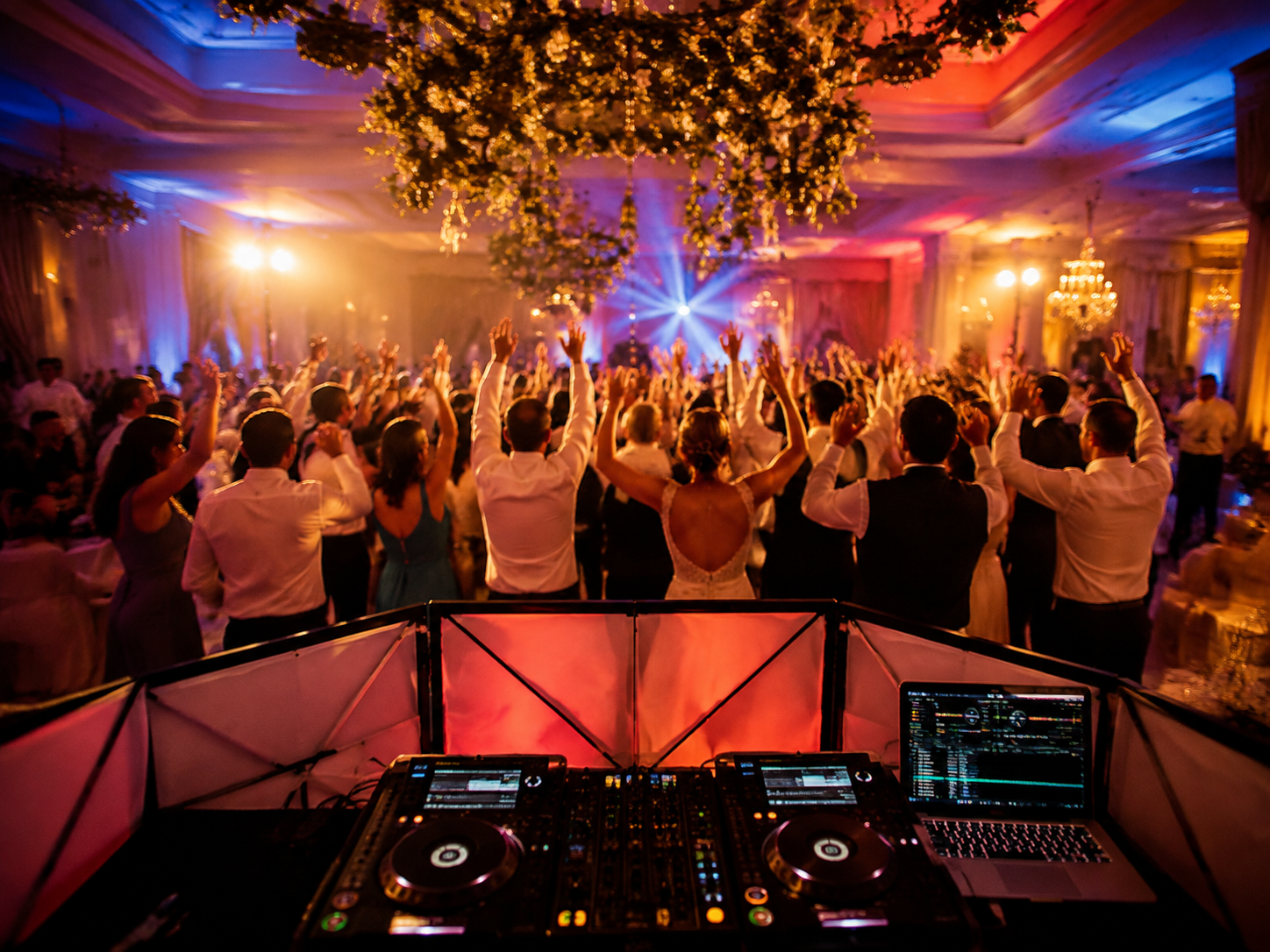 Wedding guests celebrating on a dance floor viewed from the DJ booth