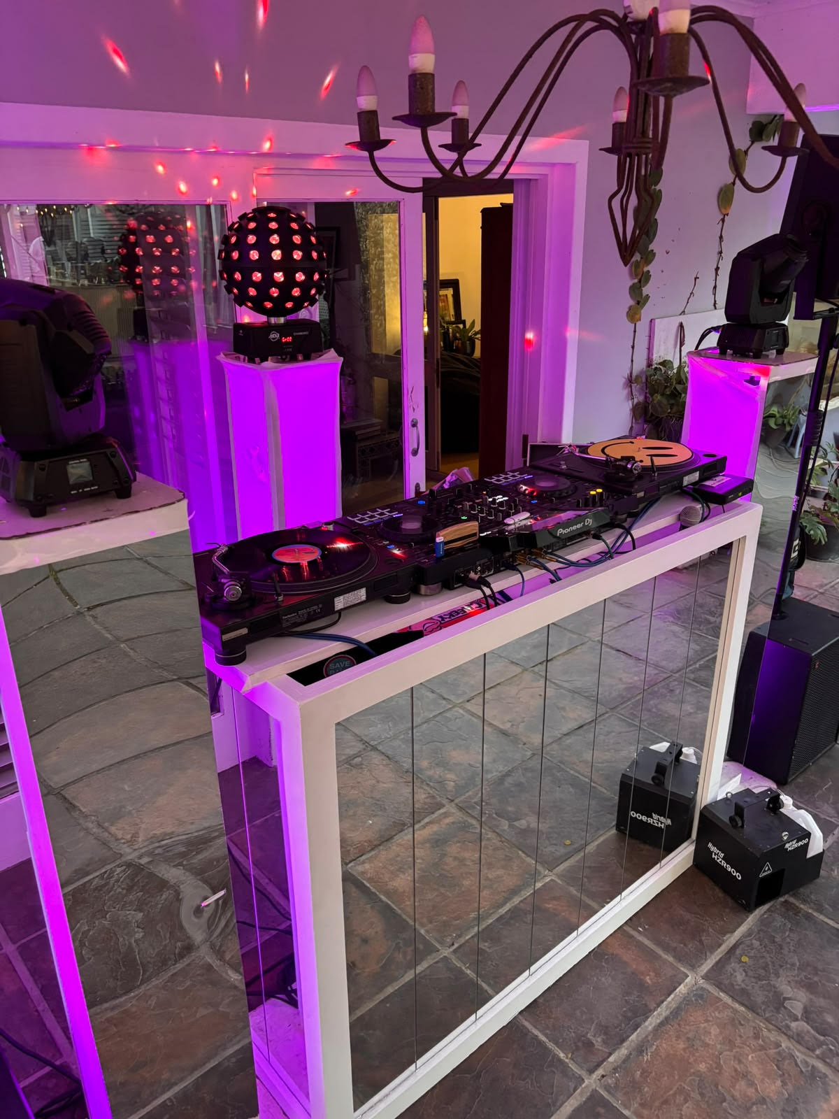 Vinyl turntables and mixer on a mirrored DJ booth with purple party lighting at Mandy’s birthday celebration